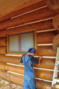A person is painting the log cabin.