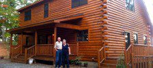 Two people standing in front of a log cabin.
