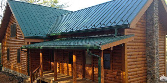 A large wooden house with green roof and wood deck.