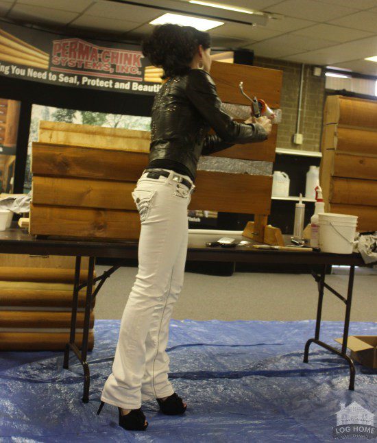 A woman standing in front of a table holding something.