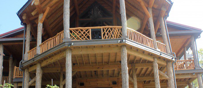 A large wooden house with a balcony and hot tub.