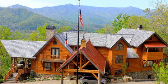 A large wooden house with american flags on the roof.