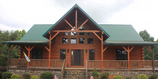 A large log home with green roof and stairs.