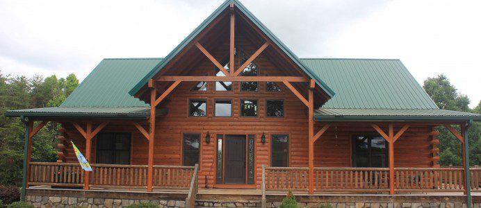 A large log home with green roof and stairs.