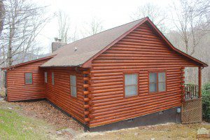 A log cabin with red wood siding and brown roof.