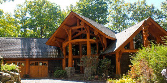 A log home with a large driveway and garage.