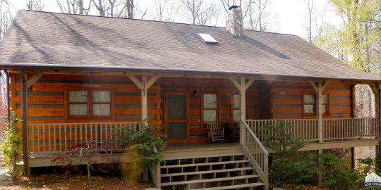 A log cabin with steps leading to the front porch.