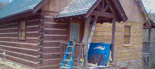 Blue ladder propped against log cabin porch